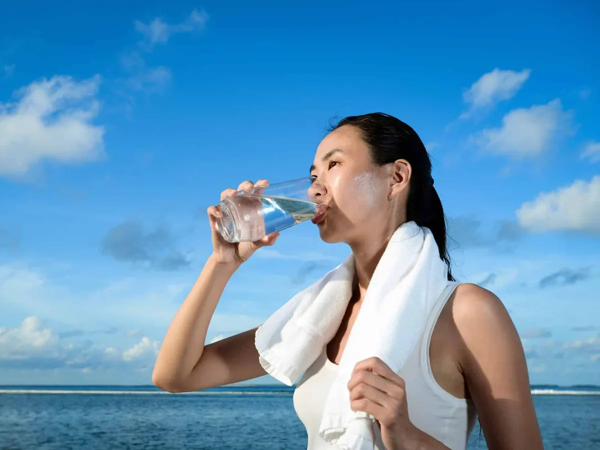 woman drinking water on the beach
