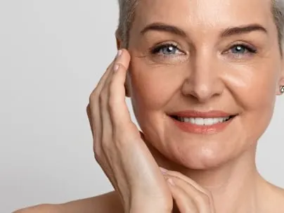 A smiling mature model with short hair touches her cheek