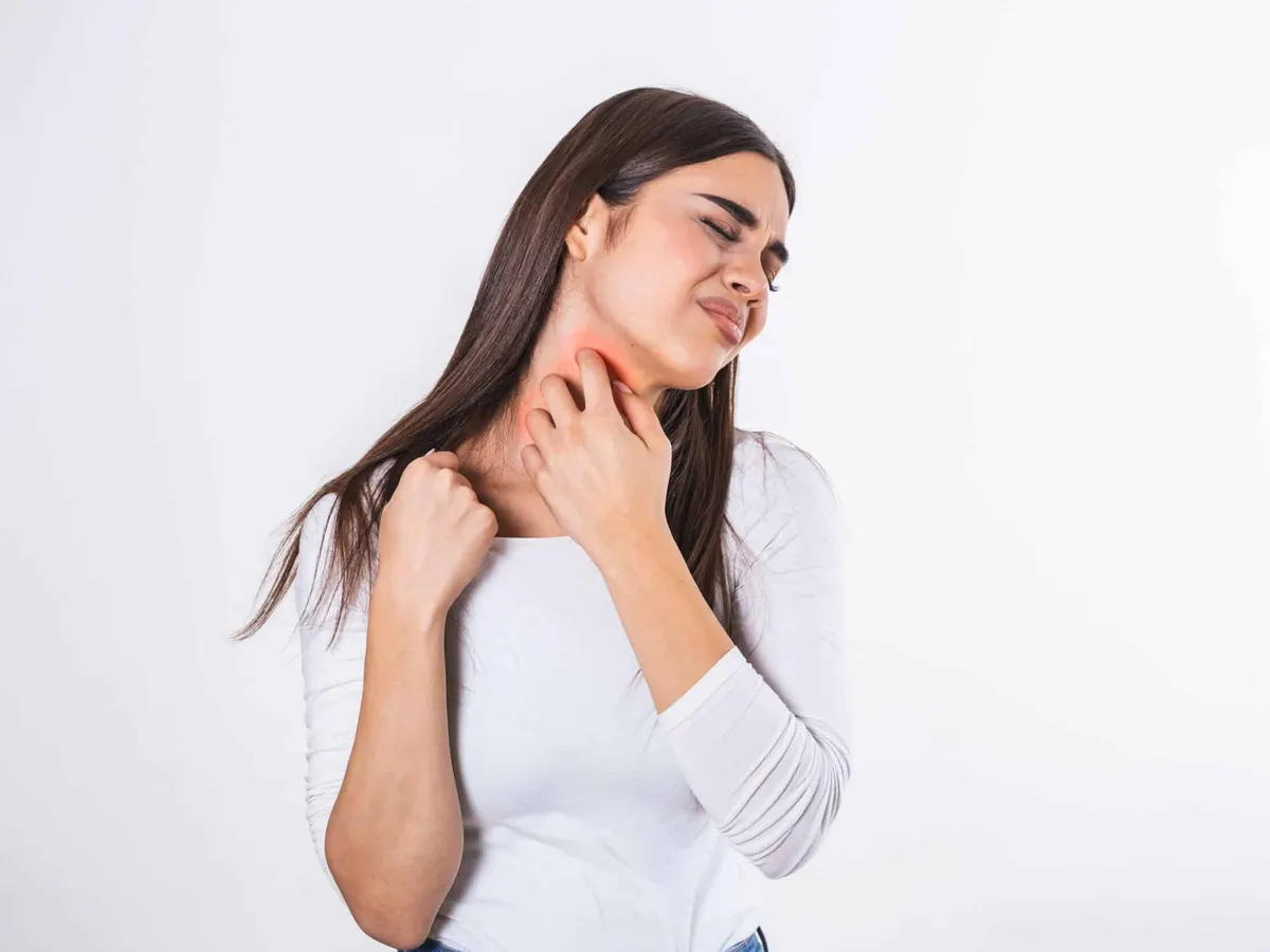 Una mujer se rasca el cuello debido a un brote de psoriasis