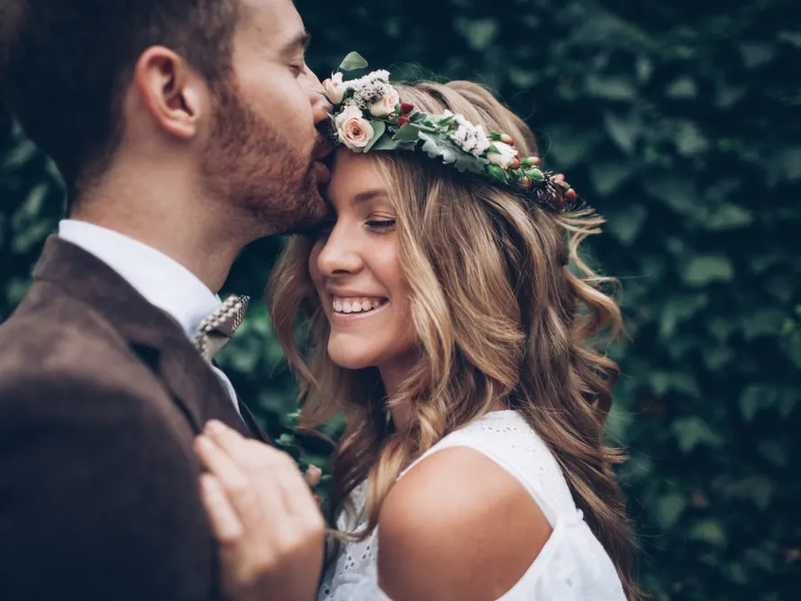 Bride with beautiful, young looking skin as she takes photo with groom