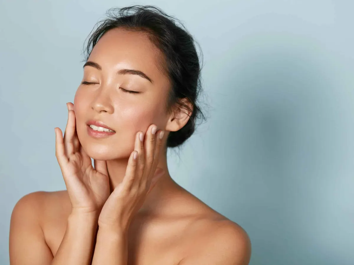 Woman touching her face with radiant skin after IPL treatment.