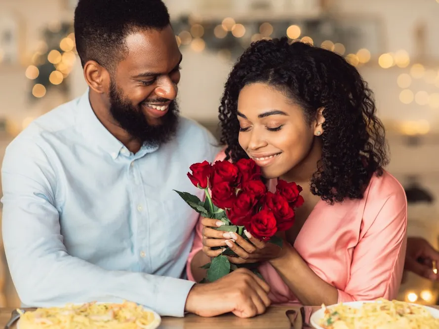 Young couple on date for valentine's day, woman smelling roses