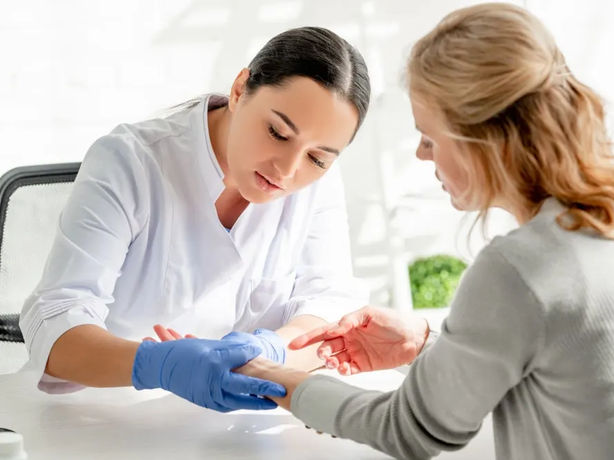 Dermatologist looking at scar on woman's arm to discuss treatment options