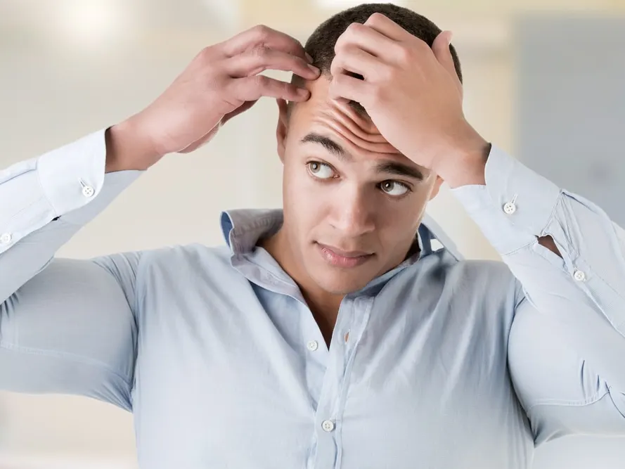 Man checking his hairline in a bathroom mirror