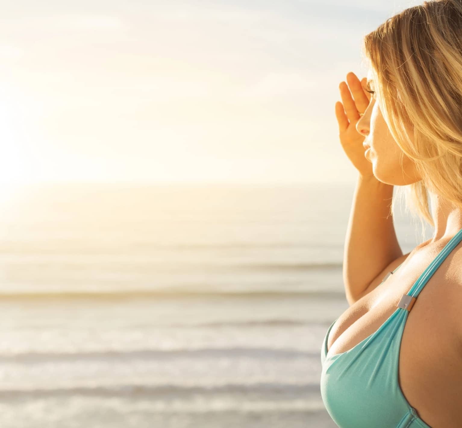 A model shading her eyes from the bright sun on a beach