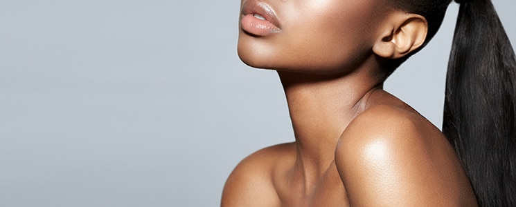 A woman's chin, neck and bare shoulder in profile, with her dark hair in a ponytail