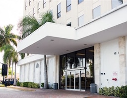 The Hallandale office building entrance under its canopy, with palm trees