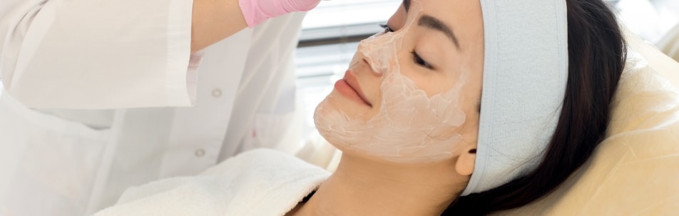 A model with a cream mask on her face lies back during a facial