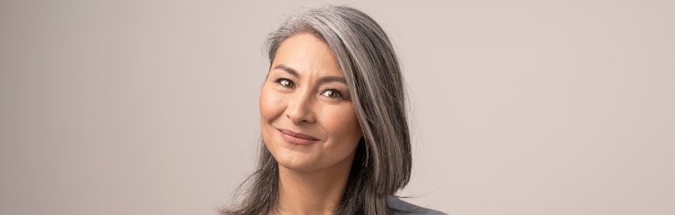 A smiling model with long gray hair