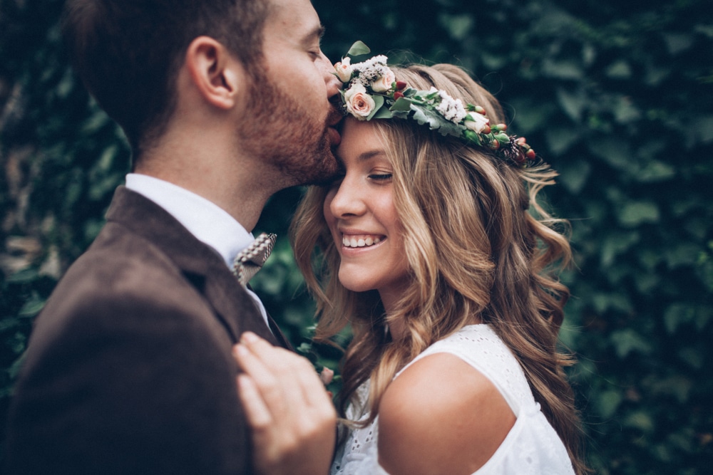 Bride with beautiful, young looking skin as she takes photo with groom