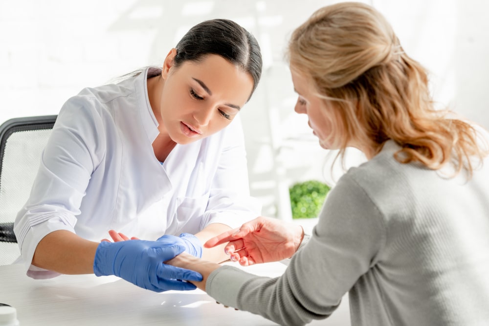 Dermatologist looking at scar on woman's arm to discuss treatment options