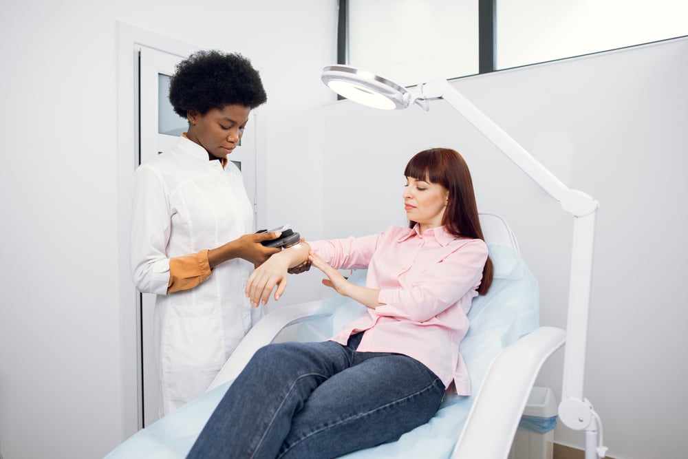 Dermatologist examining a woman's arm for skin conditions