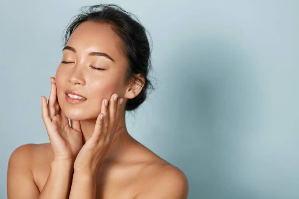 Woman touching her face with radiant skin after IPL treatment.