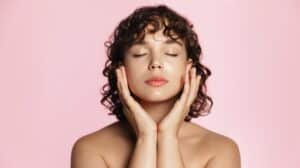 Young woman with glowing skin gently touching her face after a chemical peel treatment