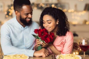 Young couple on date for valentine's day, woman smelling roses