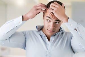 Man checking his hairline in a bathroom mirror