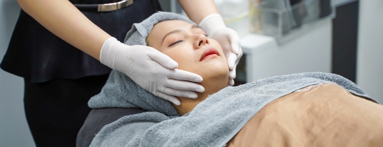 Woman receiving a professional facial treatment from an esthetician in a skin care clinic.