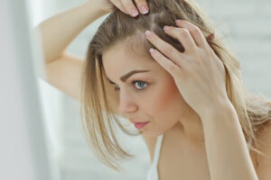 Woman examining her scalp for signs of hair thinning.